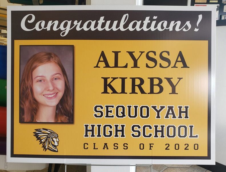 Graduation sign in yellow and black lettering.